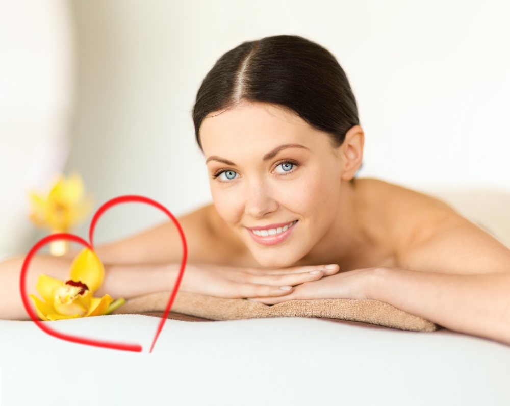 health and beauty, resort and relaxation concept - smiling woman in spa salon lying on the massage desk