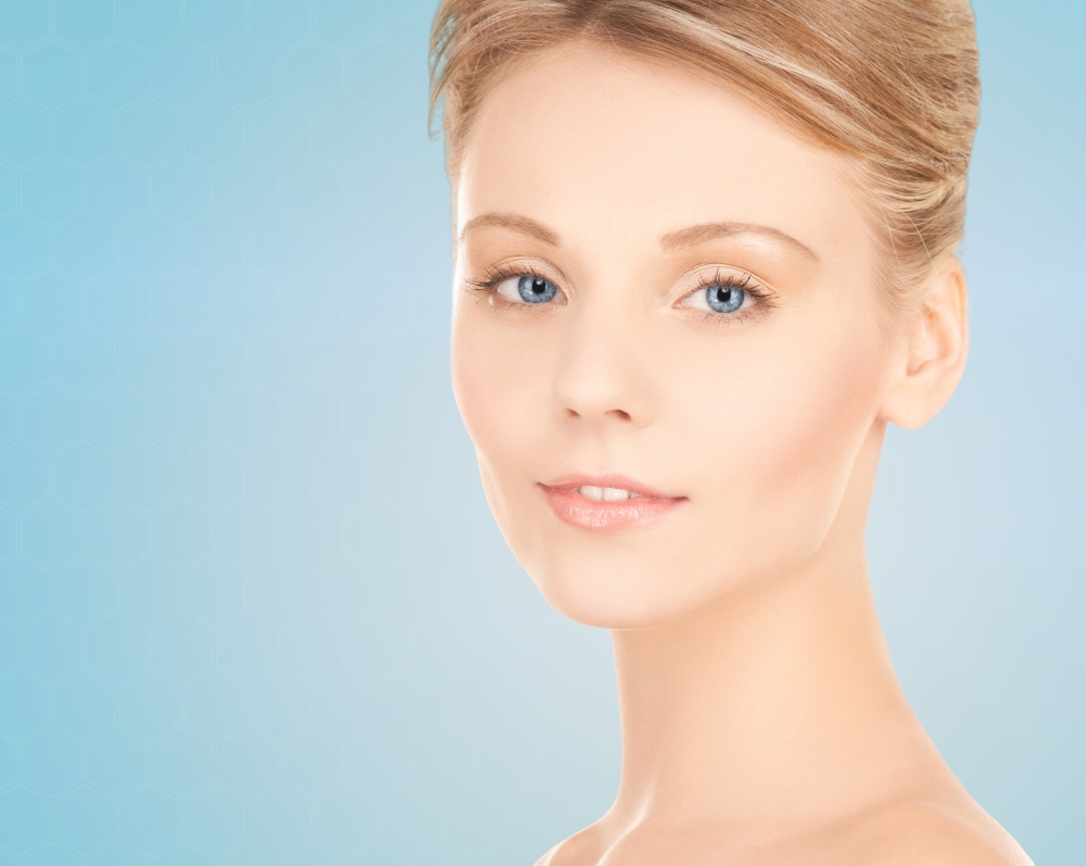 beauty, people and health concept - beautiful young woman face over blue background