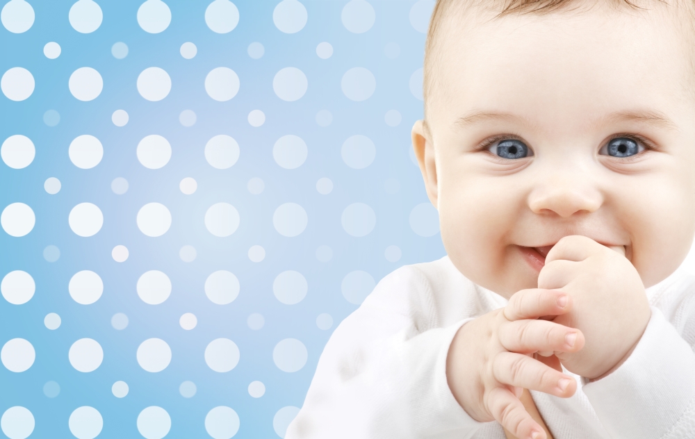 childhood, people and happiness concept - smiling baby boy face over blue and white polka dots pattern background