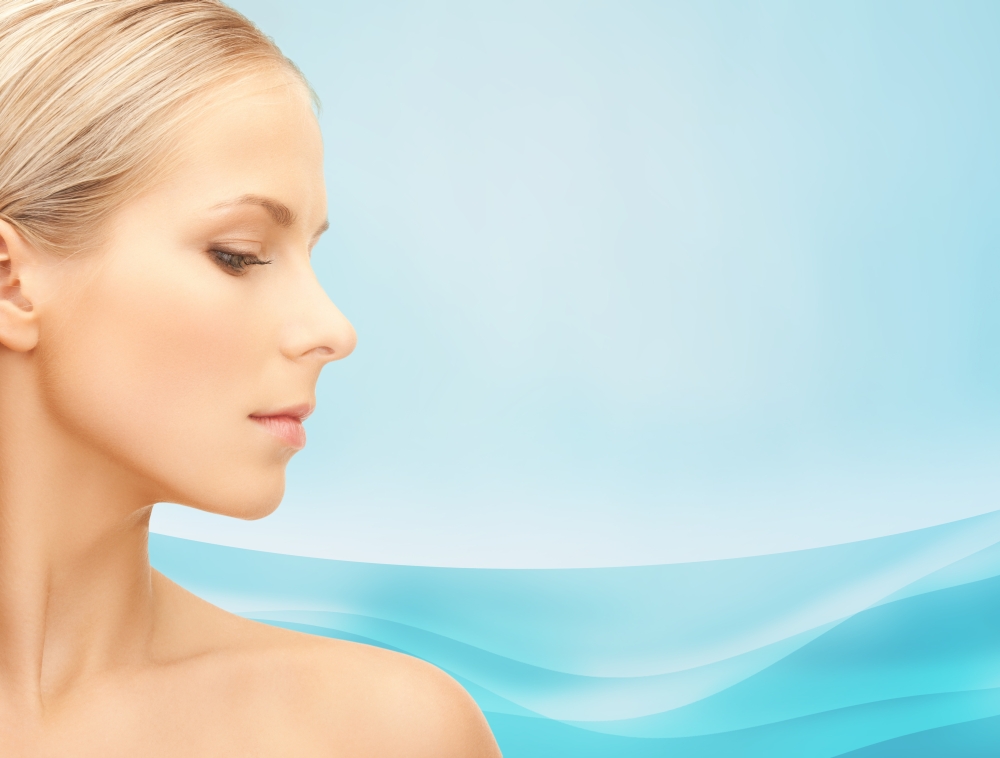 beauty, people and health concept - beautiful young woman face over blue waves background
