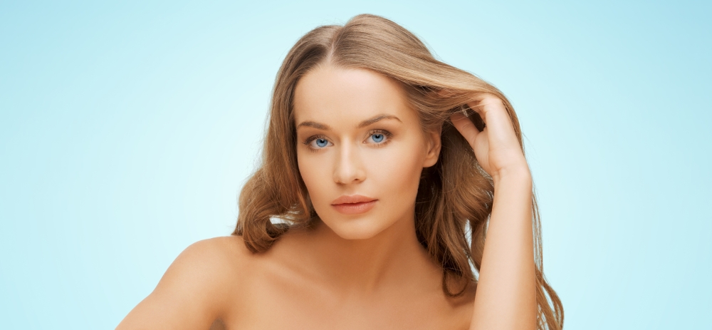 beauty, people, hair care and health concept - beautiful young woman face over blue background
