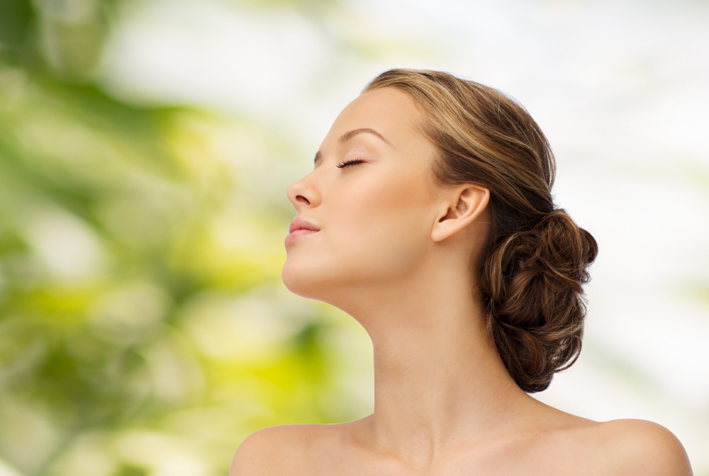 beauty, people and health concept - young woman face with closed eyes and shoulders side view over green natural background