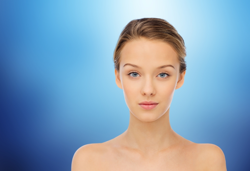 beauty, people and health concept - young woman face and shoulders over marine blue background