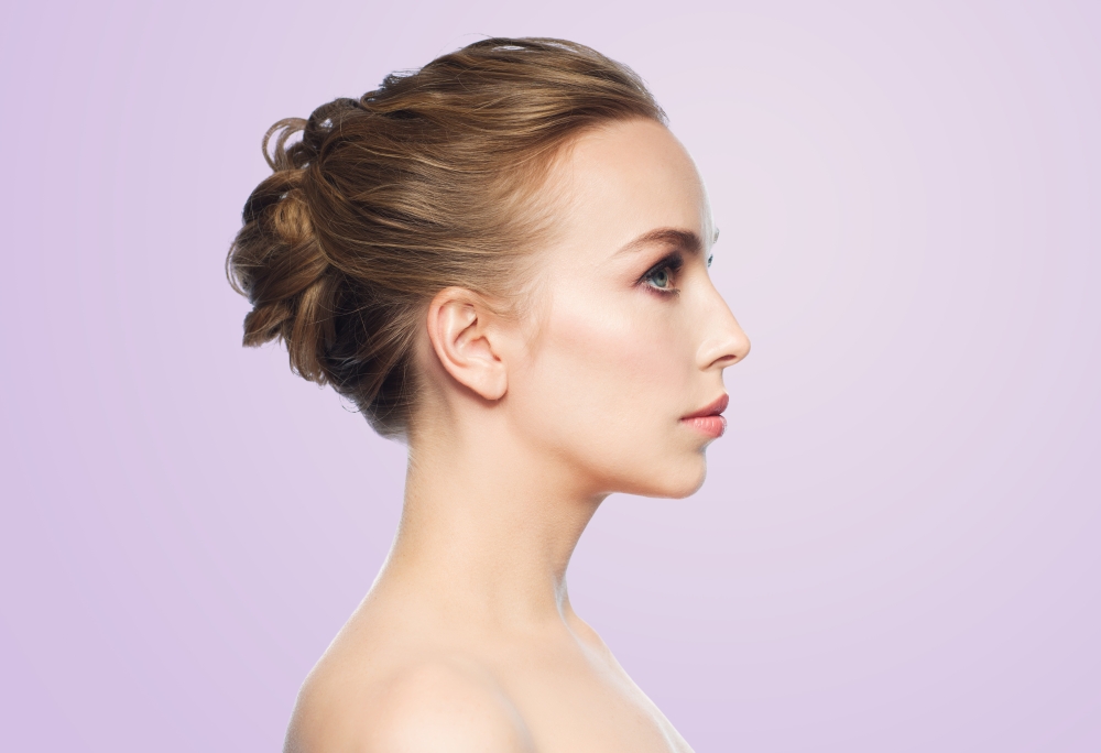 health, people, plastic surgery and beauty concept - beautiful young woman face over violet background