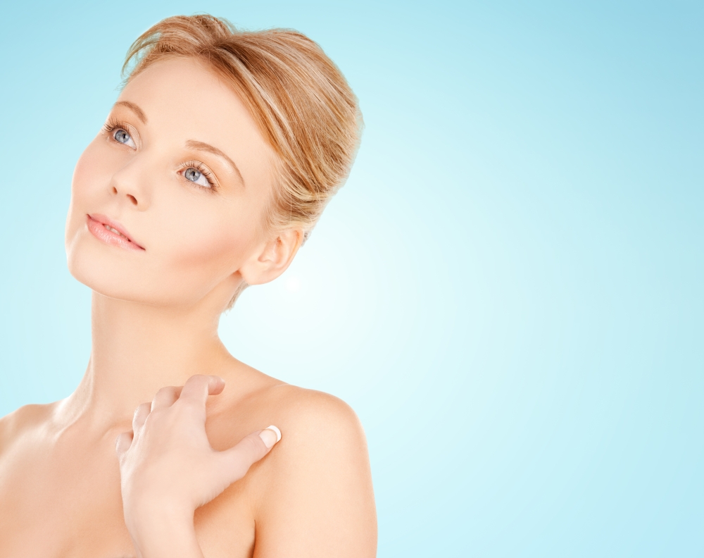 beauty, people and bodycare concept - beautiful young woman face and hands over blue background