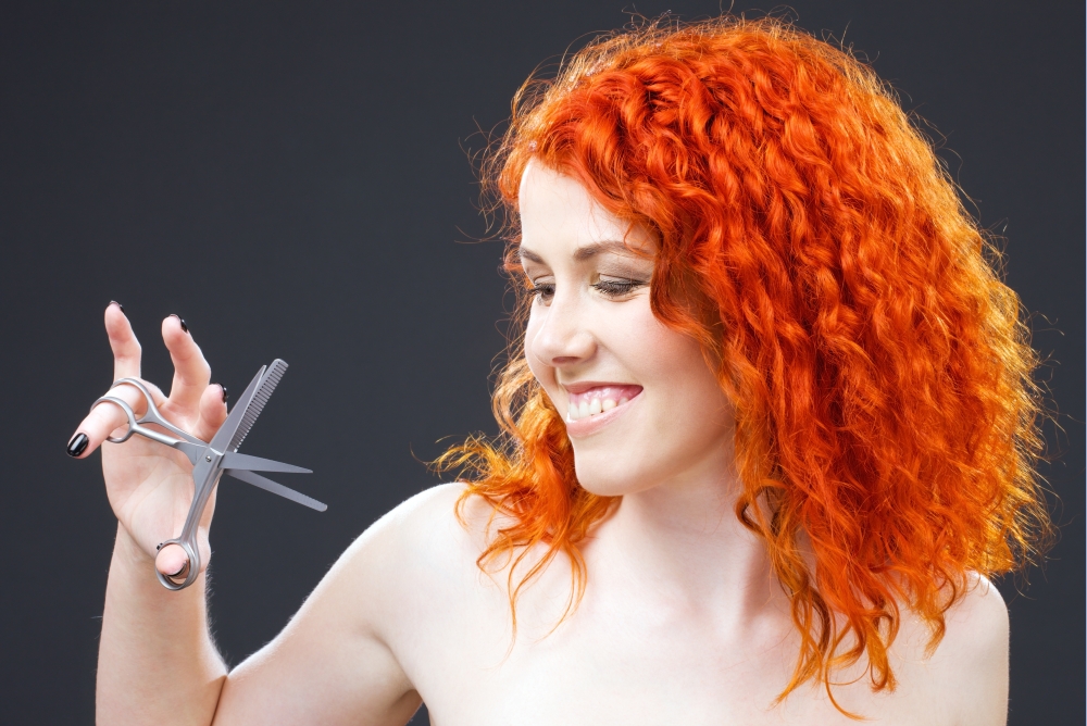 picture of lovely redhead with scissors over grey