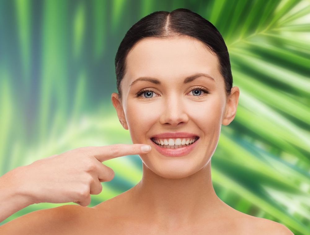 health, spa and beauty concept - clean face of beautiful young woman pointing to her mouth