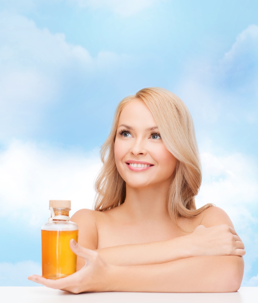 health and beauty concept - happy woman with oil bottle