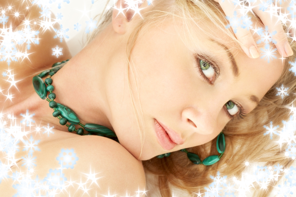 portrait of laying green-eyed blond girl with snowflakes
