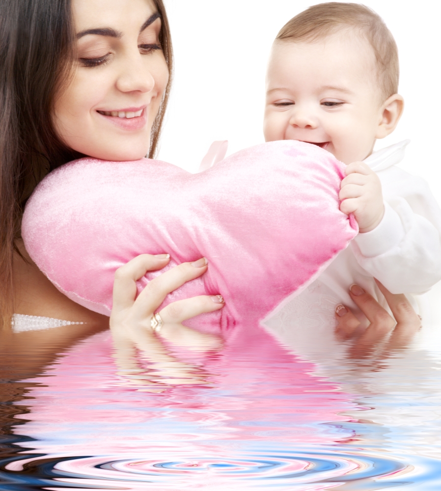 happy baby and mama with heart-shaped pillow in water