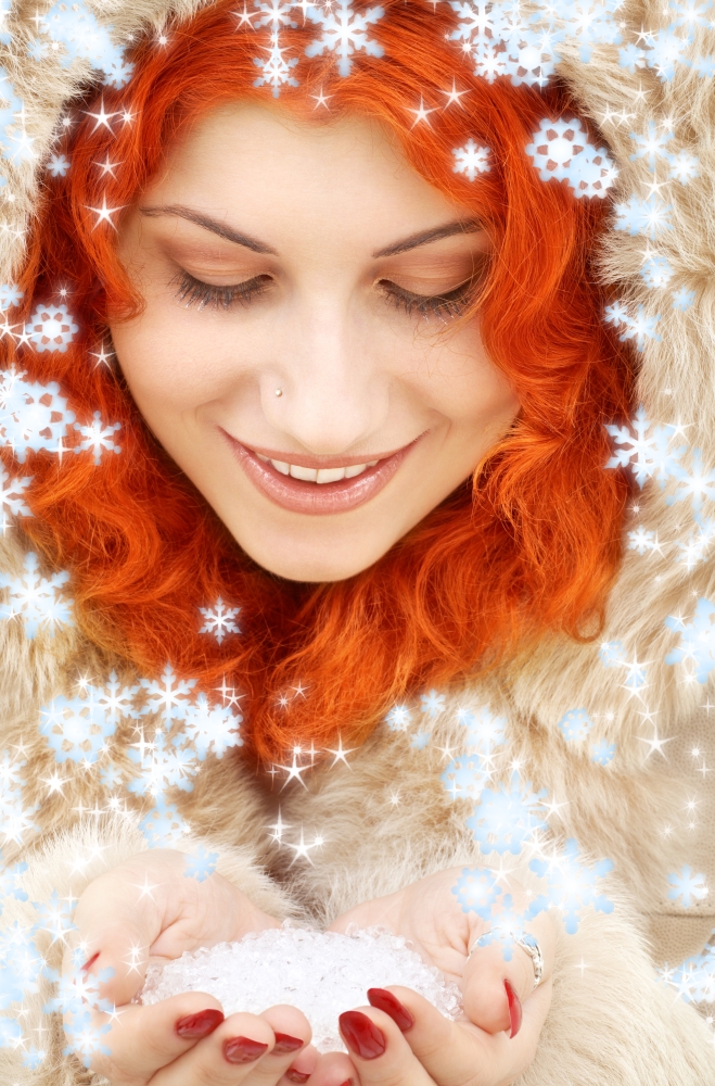 lovely redhead in fur with handful of ice and snowflakes