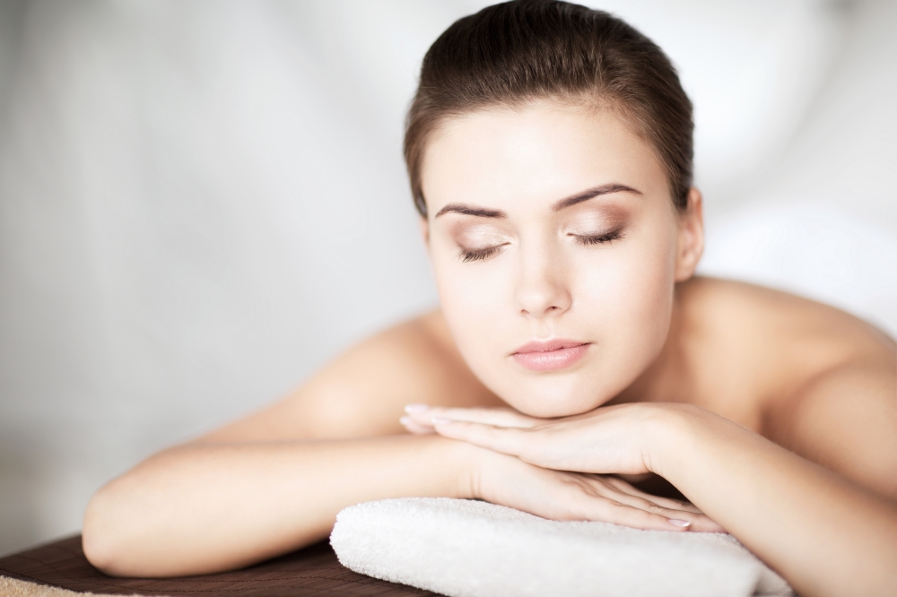beauty and spa concept -  woman in spa salon lying on the massage desk