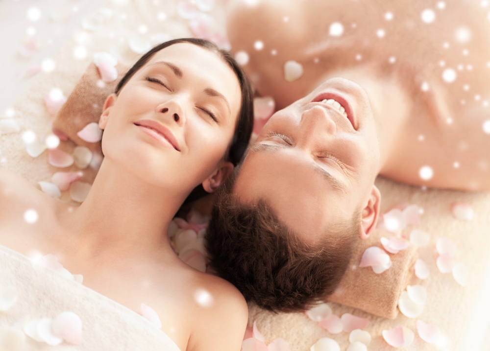 beauty, health, holidays, people and spa concept - happy couple with closed eyes lying in spa salon