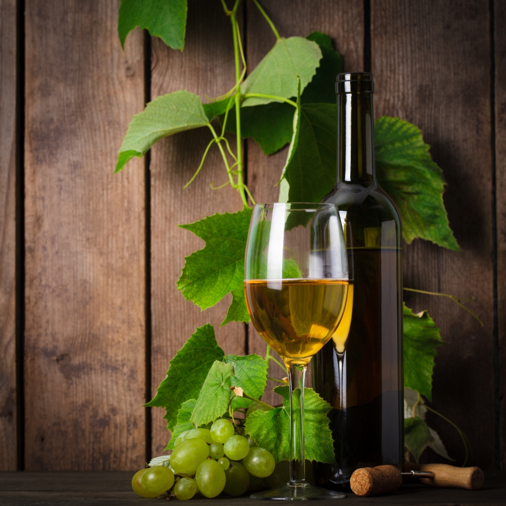 White wine, grapes, corkscrew, and bottle on wood background closeup
