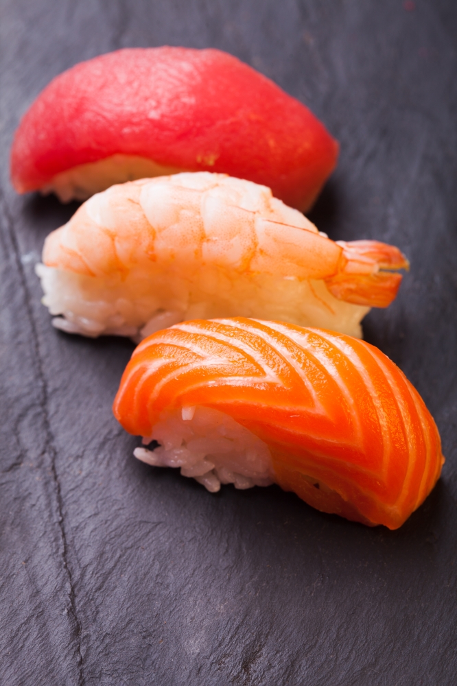 Close-up of set of tree sushi with salmon, tuna and shrimp on a black background
