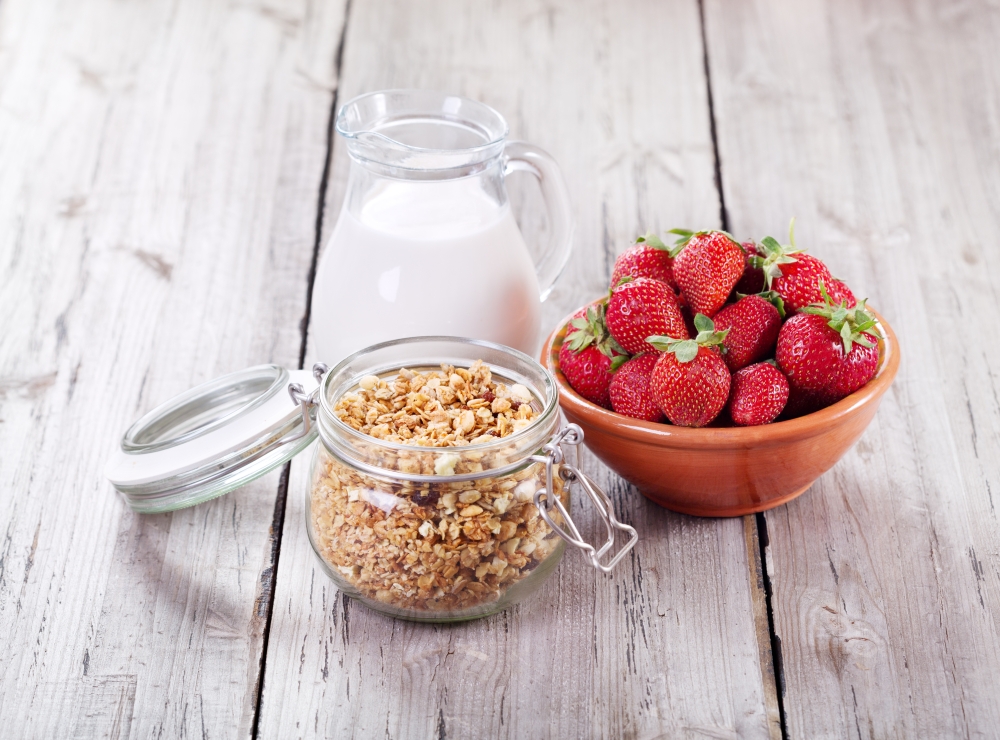 breakfast with cereals, milk and strawberries on wooden table
