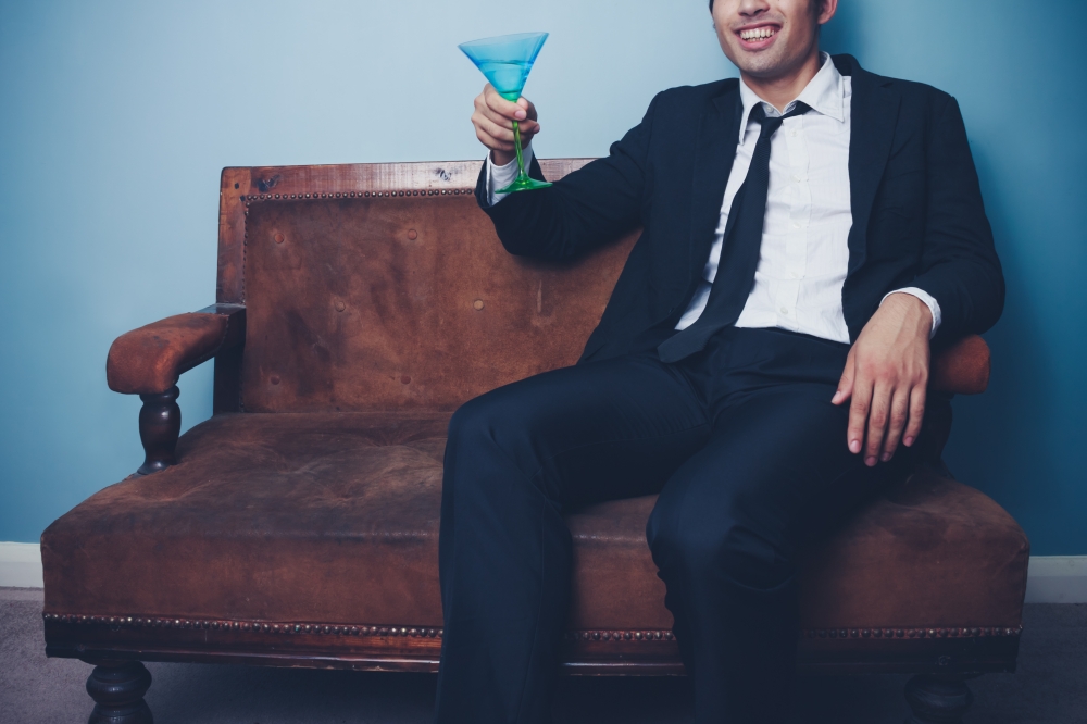 Young businessman sitting on sofa with cocktail glass