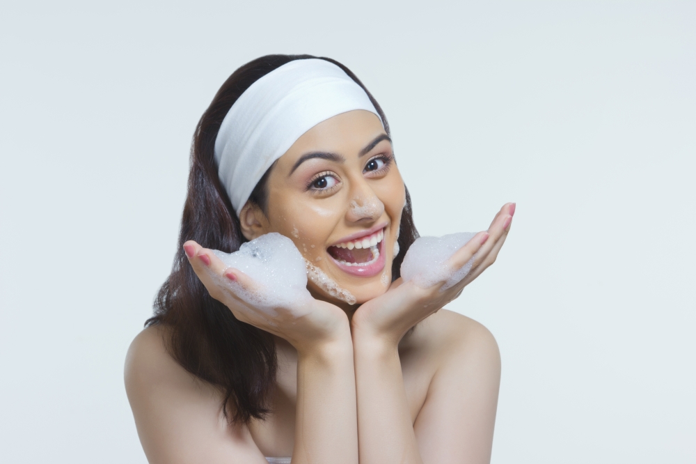 Portrait of happy woman with soap sud against gray background