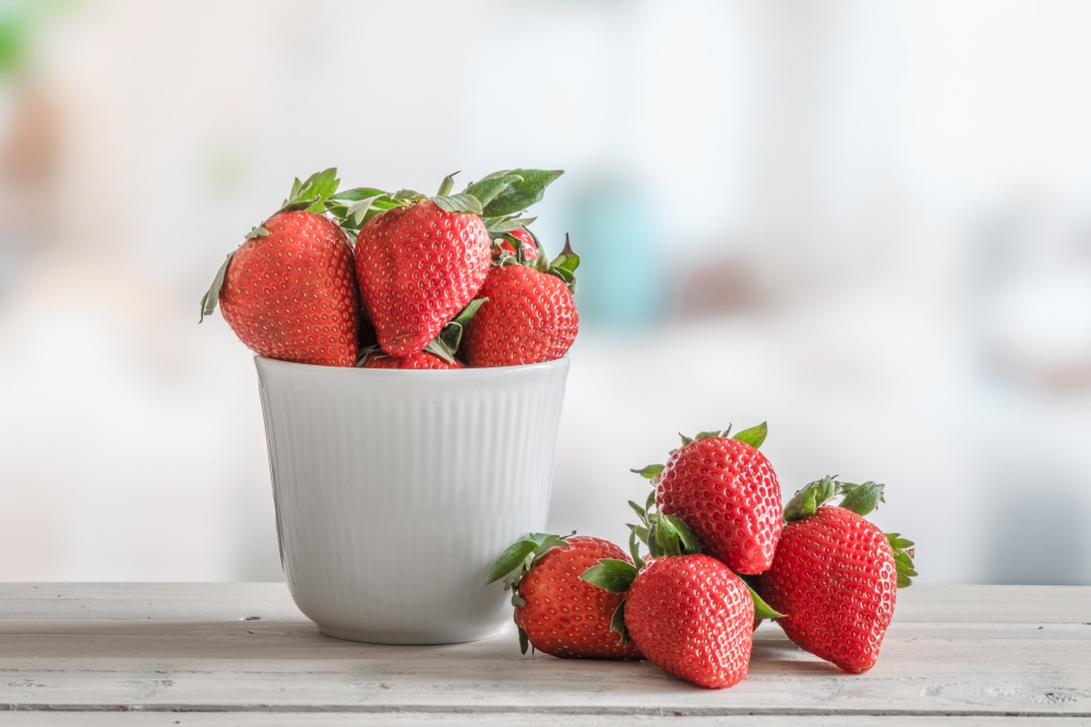 Strawberries in a white bowl on a wooden table