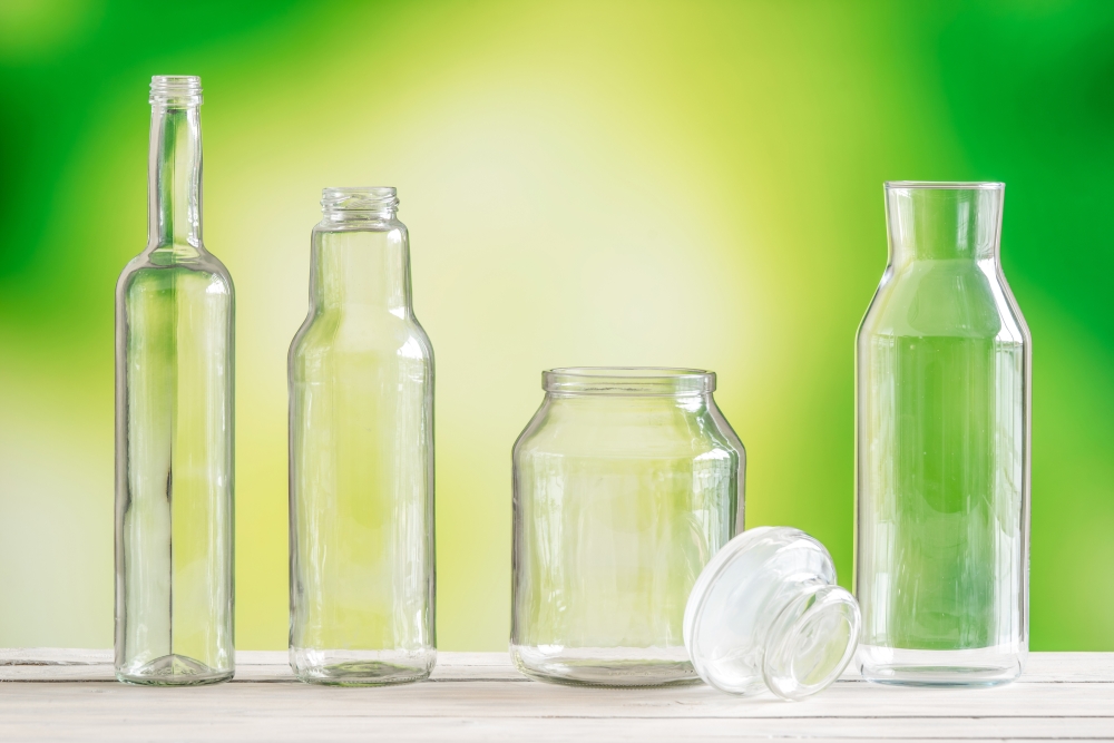 Empty glass bottles on a table on green background