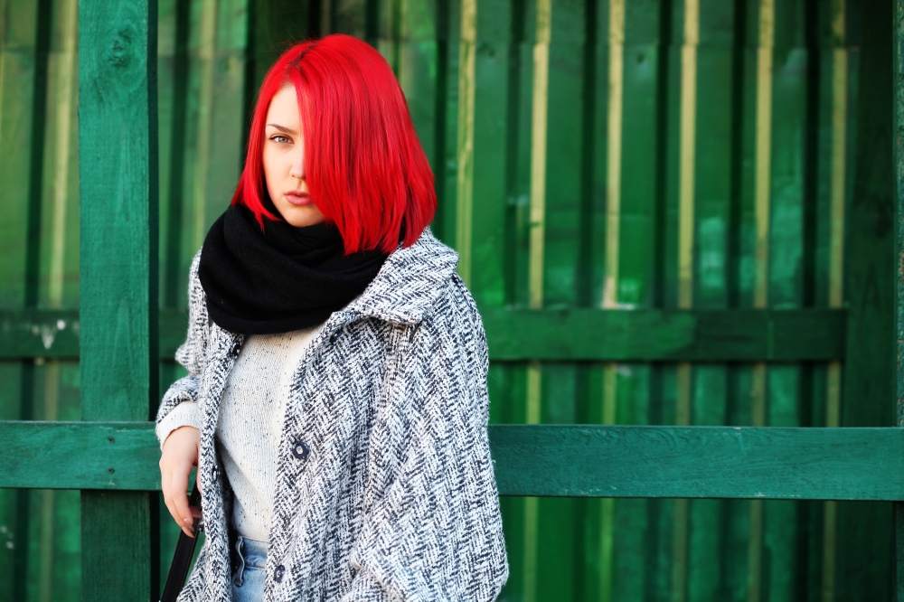 Beautiful red haired woman posing outdoors. Street style.