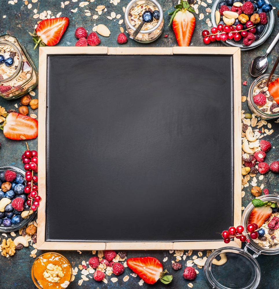 Muesli and berries around black blank chalkboard background. Healthy breakfast concept. Detox and Clean food concept.