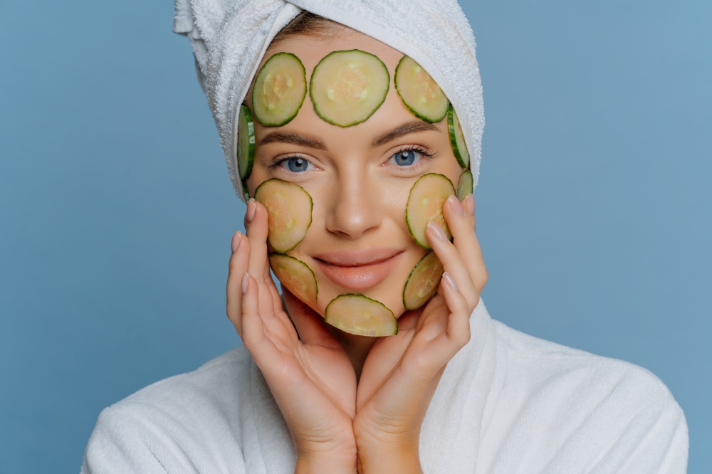 Smiling woman adorned with cucumber slices, depicting rejuvenation and playful beauty.