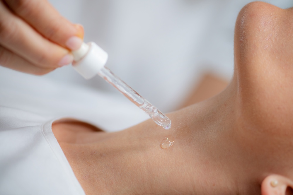Cosmetician applies hyaluronic acid serum on woman&rsquo;s neck for targeted anti-aging benefits, enhancing skin elasticity and firmness
