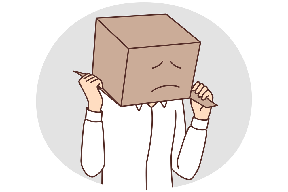 Man with cardboard box on head with painted sad face. Sad guy in white shirt hides head behind parcel for concept of problems with courier company or delivery service. Man with cardboard box on head with painted sad face due problems with courier company