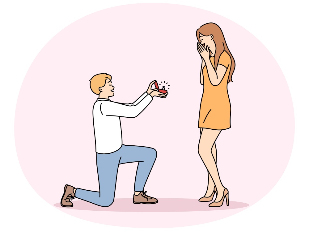 Man in love kneeling down, gives ring to beloved offering to marry and play wedding. Happy girl feels embarrassed covering mouth with hand after wedding proposals from boyfriend. Man in love kneeling down, gives ring to beloved, offering to marry and play wedding