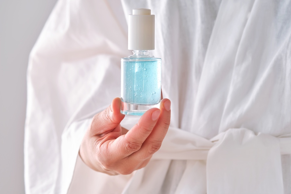 Blue serum with pipette in a womans hands in a robe. High quality photo.. Blue serum with pipette in a womans hands in a robe.