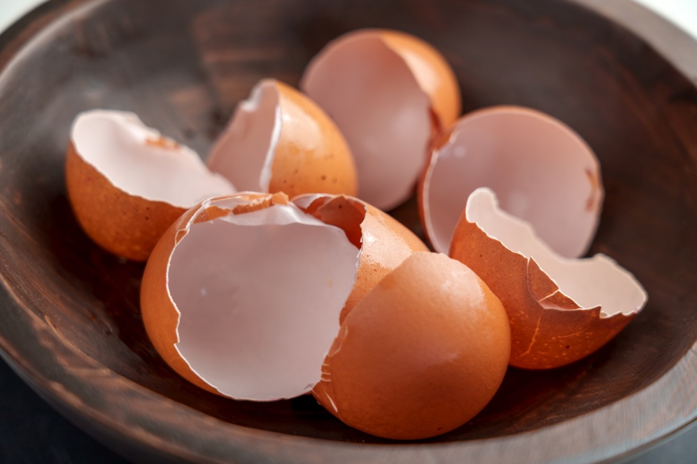 Broken eggshells of chicken brown eggs in wooden kitchen bowl. Organic garbage. Separate waste collection concept.