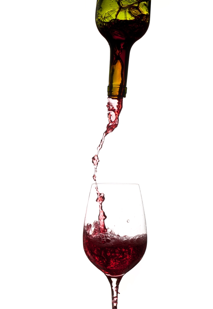 Red wine being poured directly from bottle into a large goblet