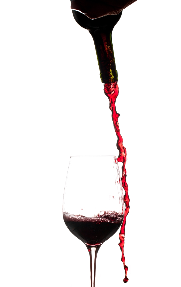 Red wine being poured directly from bottle into a large goblet and missing
