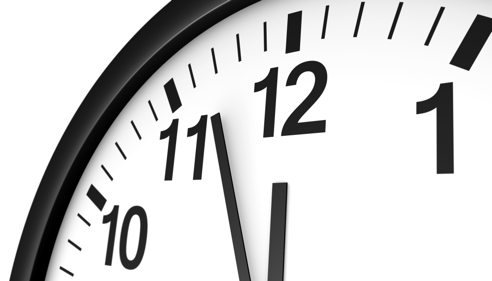 Time concept with a close-up face view of a black and white wall clock with clean design showing almost midnight hour.